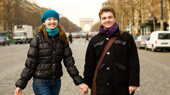 世界のバレンタインデーに関するブログのイメージフォト。フランスのバレンタインデーを説明する画像。凱旋門が見える並木道で手をつなぐ笑顔のカップル。